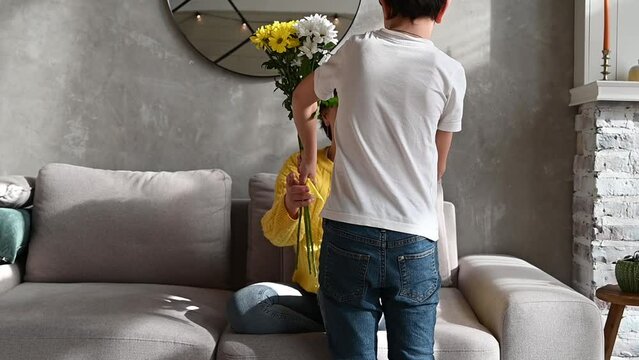 happy mother's or women's day concept. child son congratulates mother on holiday and gives flowers