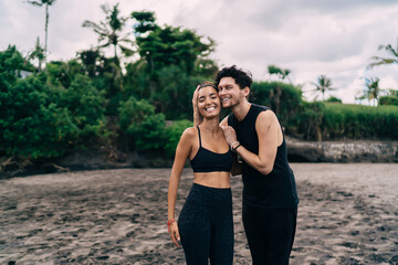 Diverse couple in love rejoicing at seashore and smiling at camera during together vacations in Indonesia, half length portrait of cheerful male and female best friends enjoying leisure at coastline