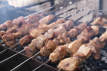 a man roasts meat on a fire. Close-up of hands and barbecue. Grilling pork neck. Roasted carrots....