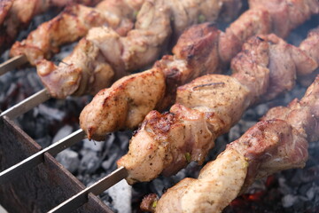 
a man roasts meat on a fire. Close-up of hands and barbecue. Grilling pork neck. Roasted carrots. Fatty food, festive food of the CIS countries. May 1, working day. Non vegan food. Street food, cooki