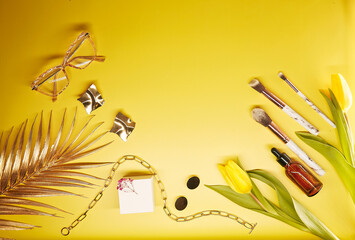 Trendy cosmetics, accessories, makeup brushes and accessories on yellow background. Box mockup, tulips, glasses, serum dropper, decorations and copy space.