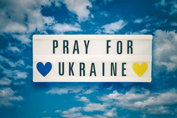 PRAY FOR UKRAINE written in a lightbox on clouds sky background