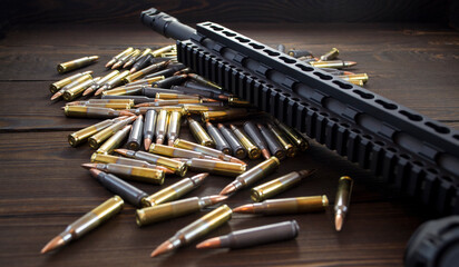 Collimator gunsight and black barrel of legendary u.s. machine gun with 5.56 ammo brass on wooden vintage background