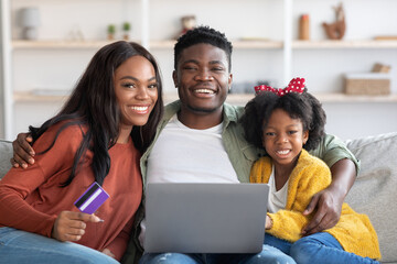 Online Bookings. Portrait Of Happy Black Family With Laptop And Credit Card