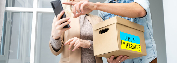 Close up of volunteer cyrrying box with Humanitarian aid for Ukrainian refugees in street