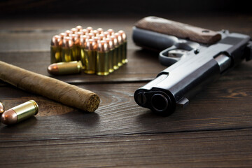 Legendary U.S. Army handgun Colt 1911A1 with .45 bullets and a cigar on wooden background, gangster...