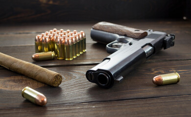 Legendary U.S. Army handgun Colt 1911A1 with .45 bullets and a cigar on wooden background, gangster...