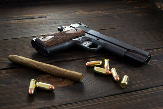 Gun with .45 bullets and a cigar on wooden background, gangster mafia concept
