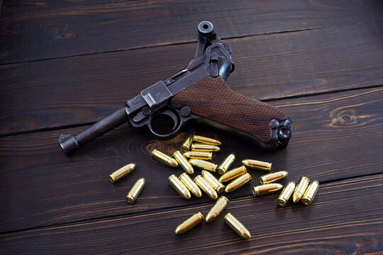 Historic Luger P08 Parabellum handgun, old soviet TT handgun and shiny 9 mm bullets on wooden vintage background