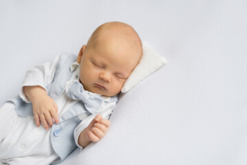 newborn baby boy in a suit sleeping on a  white background. Happy pregnancy and childbirth. Health concept.