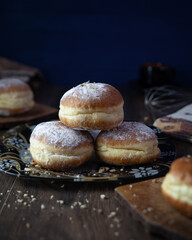There are donuts on the table in a plate. Sprinkled with powder.On a blue background. Selective focus.