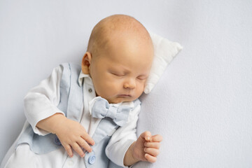 newborn baby boy in a suit sleeping on a  white background. Happy pregnancy and childbirth. Children's theme. Top view