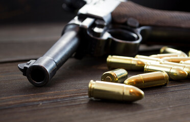 Historic Luger P08 Parabellum handgun, old soviet TT handgun and shiny 9 mm bullets on wooden vintage background