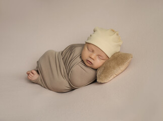 a newborn baby sleeps on a pillow  on a beige background