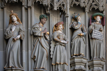 Stone statues by entrance of Swiss medieval cathedral in Bern. Decoration of facade of evangelical church in Bern. Gothic sculptures, architectural elements of Bern minster.