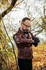 A stylishly dressed man with glasses, a beautiful autumn forest and a river. Elderly Brit.