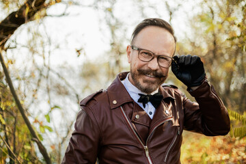 A stylishly dressed man with glasses, a beautiful autumn forest and a river. Elderly Brit.