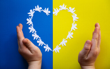 Heart, laid out of paper angels on yellow blue background in colors of Ukrainian flag, children's...