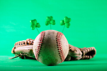 Baseball and glove with blurred clovers in green background for St. Patricks day holiday.