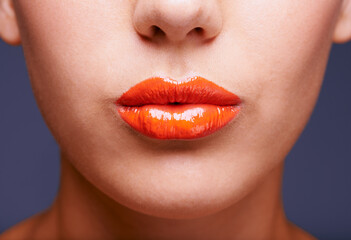Just a touch of tangerine. Cropped shot of a womans lips covered in shiny orange lipstick.