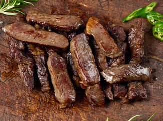 roasted piece of beef ribeye cut into pieces on a vintage brown chopping board. Well done. Appetizing steak , top view