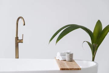 Candle and towels at wooden shelf over contemporary tub