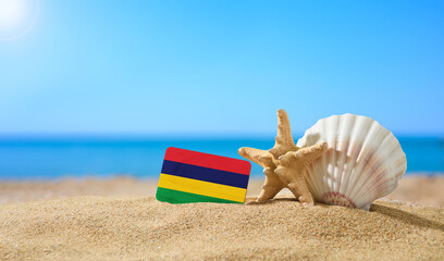 Tropical beach with seashells and Mauritius flag. The concept of a paradise vacation on the beaches...