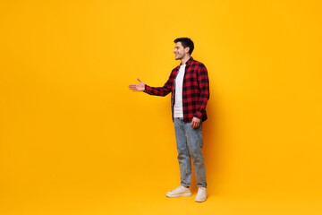 Fototapeta premium Portrait of happy young man posing at yellow studio