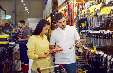 Customers shopping at a DIY store. Young married couple shopping for tools at a modern hardware...