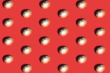 Pattern made of golden eggs on red background. Minimal Easter or food concept.