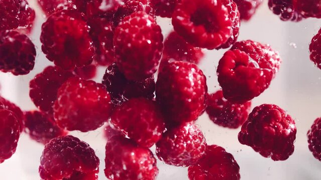 ripe raspberries splashing into water