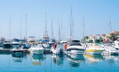 Fototapeta premium Sailing Boats and Motor Boats moored at Marina in Cyprus with residential houses on the background. Yacht harbor.