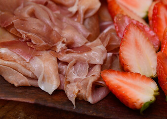 close-up of slices of ham and strawberries, cold dish, cold platter,accompaniment to wine, snack to wine