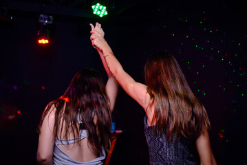 women dancing in nightclub holding hands,victory gesture, celebrating victory, girls, backwards 