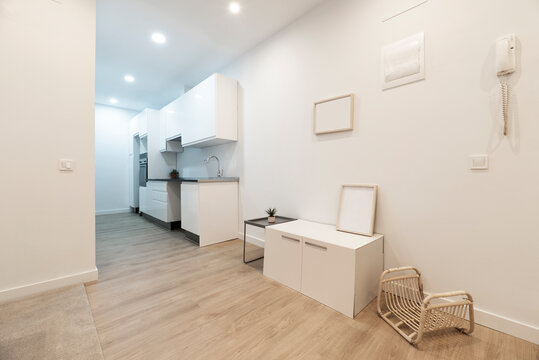 Living Room With Cabinet, Wicker Magazine Rack, Side Table And Hallway With White Kitchen With Gray Countertop In A Room With Oak Flooring