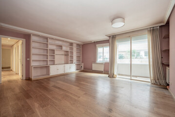 Fototapeta na wymiar Large empty living room with a terrace, parquet floors and plaster and wood shelving on a wall painted pink