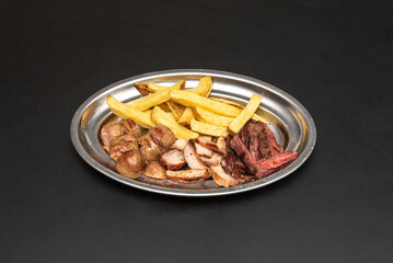 Asado of assorted meats and chorizos with homemade chips on a stainless steel plate