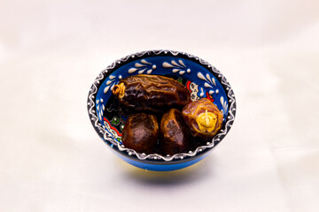Dried date fruits in the white bowl isolated on white background. Selective focus.