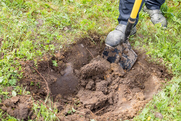 Digging the earth with a spade at countryside. Male foot wearing a rubber boot digging the earth with a spade. iron shovel stuck in the ground.preparing for garden work. photo in natural light