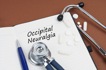 On a brown surface lie pills, a pen, a stethoscope and a notebook with the inscription - Occipital...
