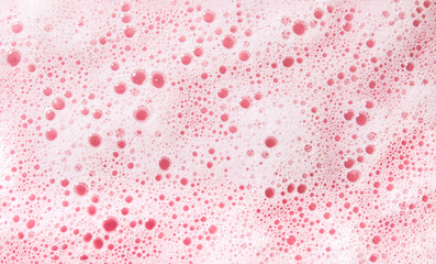 White soap foam surface or shower gel shampoo with bubbles. Abstract cosmetic pink background texture. Selective focus.