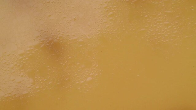 Drops falling onto the surface of homemade bone broth and waves forming