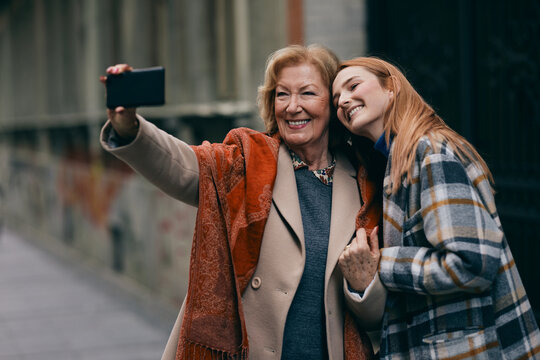 Grandmother taking selfie of her and her granddaughter. Seniors using technologies.