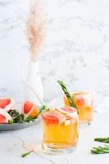 Refreshing grapefruit cocktail with rosemary in glasses on the table. homemade drink. Vertical view. Close-up