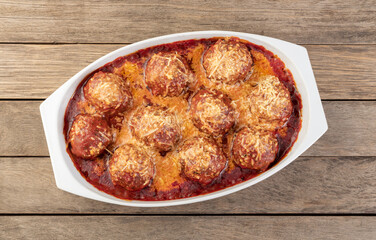 Meat balls on a white plate with tomato sauce and melted cheese