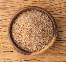 Ground whole wheat in a bowl over wooden table