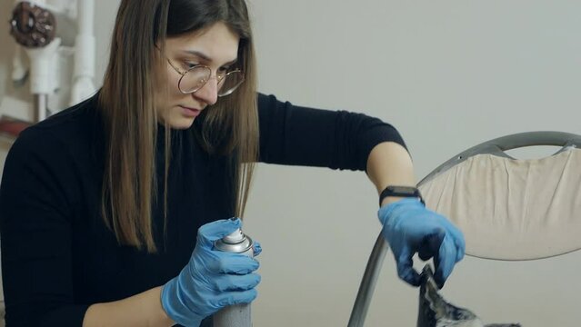 Woman spraying cleaning liquid on her shoes. Proper shoe care