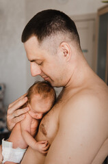 Portrait of father holding sleeping newborn son on his arm. Newborn baby in diaper in father's hands. Selective focus. Film grain