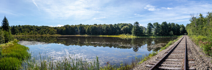 Rural New York countryside scenery showing old abandoned train tracks next to a pond in the woods