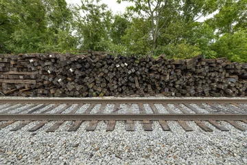 Papier Peint photo Chemin de fer Brown railroad ties piled up next to active train tracks
